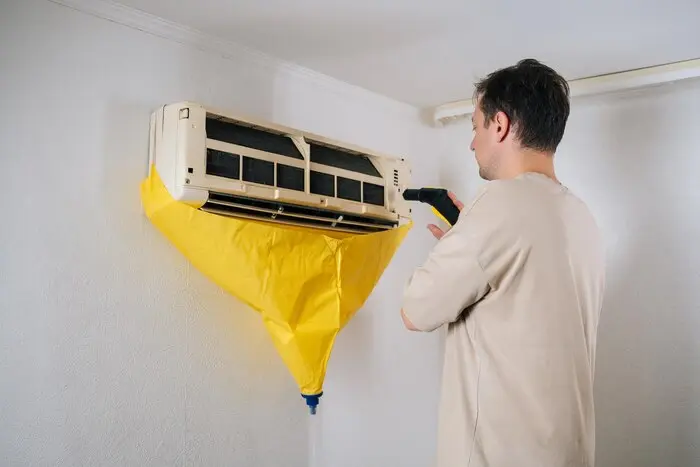 air conditioning technician cleaning air conditioner unit using steam cleaner while yellow 482921 17699