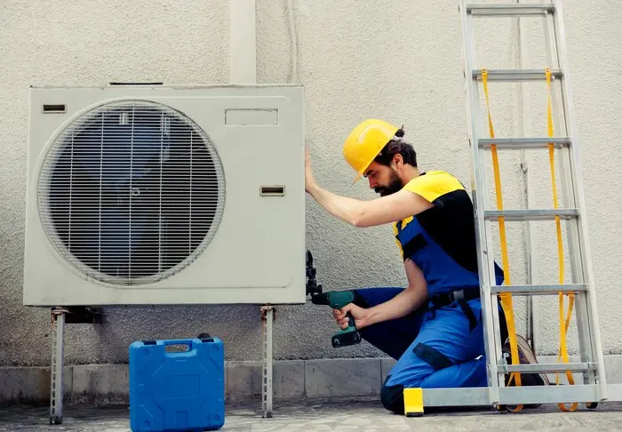 competent repairman starting work defective air conditioner using handheld drill disassemble condenser metal coil panel precise mechanic dismantling hvac system check dirt 482257 67970